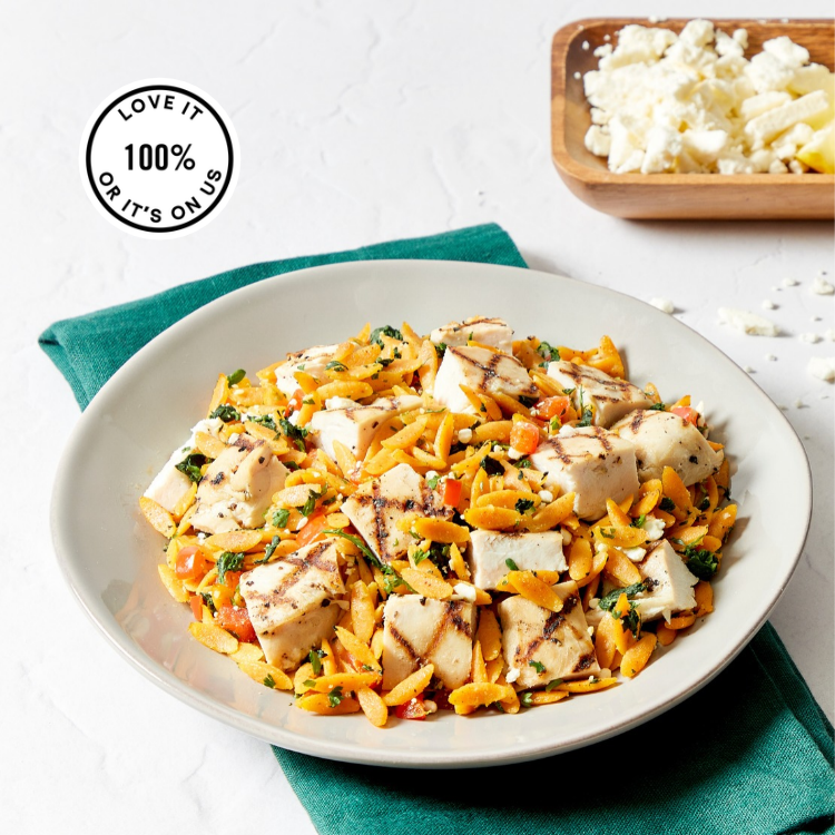 A plate showing Seasoned chicken breast, tender orzo, colorful vegetables, and creamy feta come together with a bright lemon-oregano dressing.